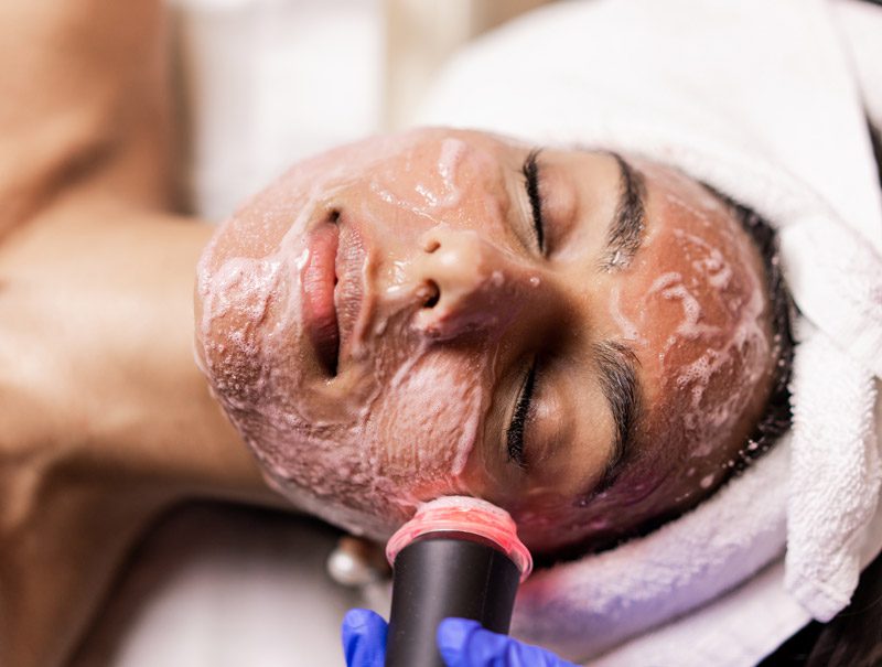 oxygeneo-face-horizontal A woman is getting her face washed with a device.