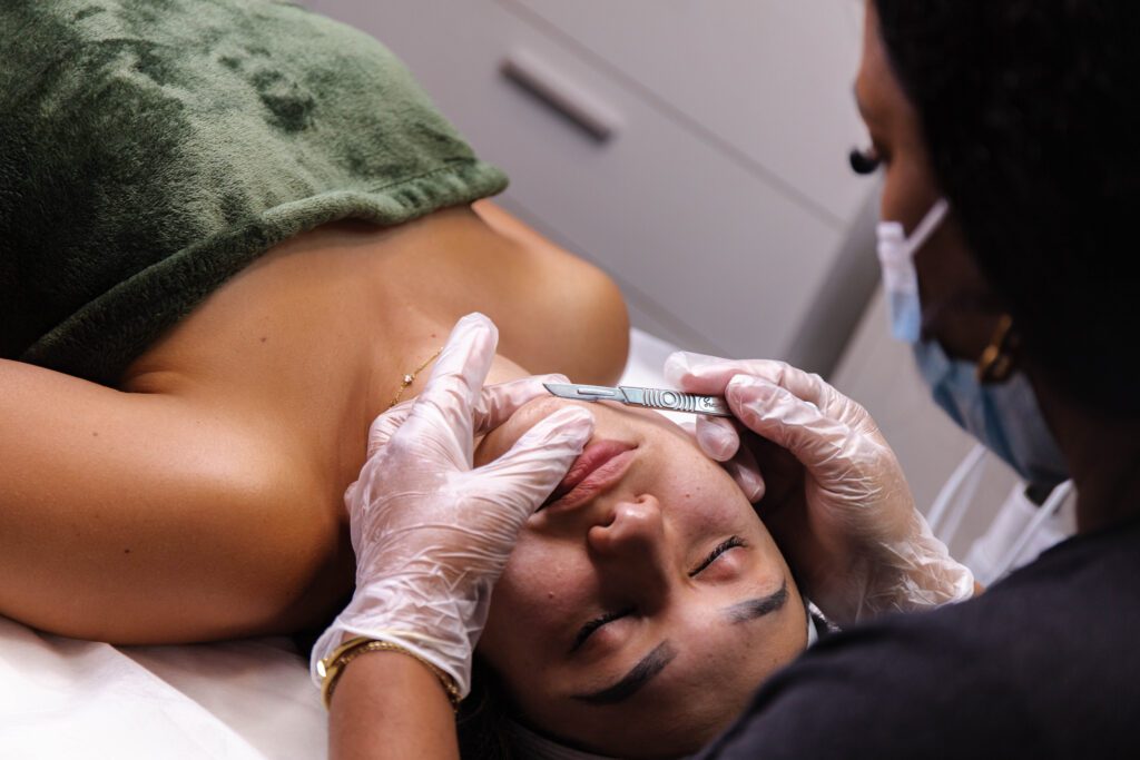 2C8A1584 (3) A woman getting her face waxed by a person in gloves.